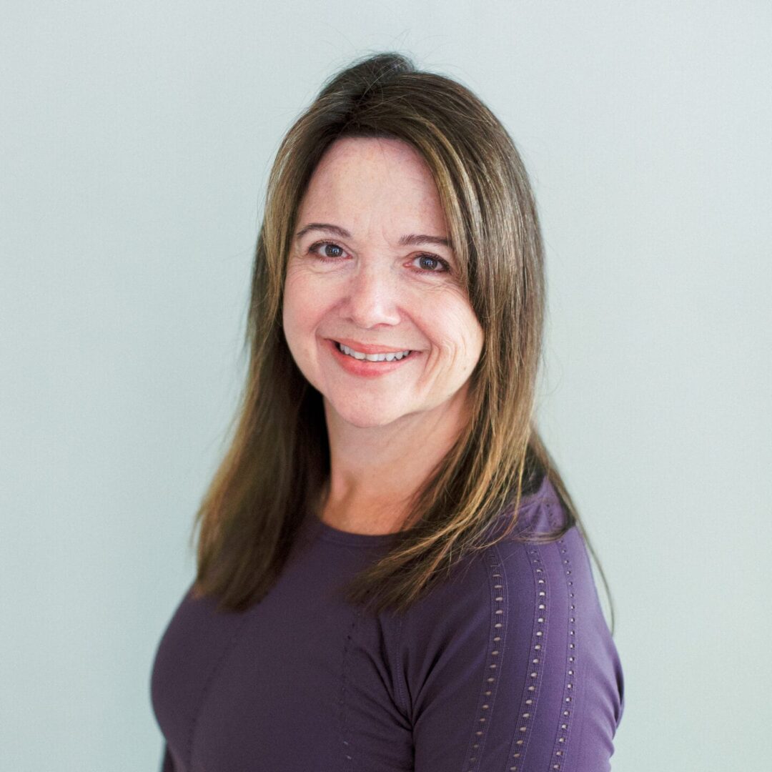 A woman with long hair wearing purple shirt.