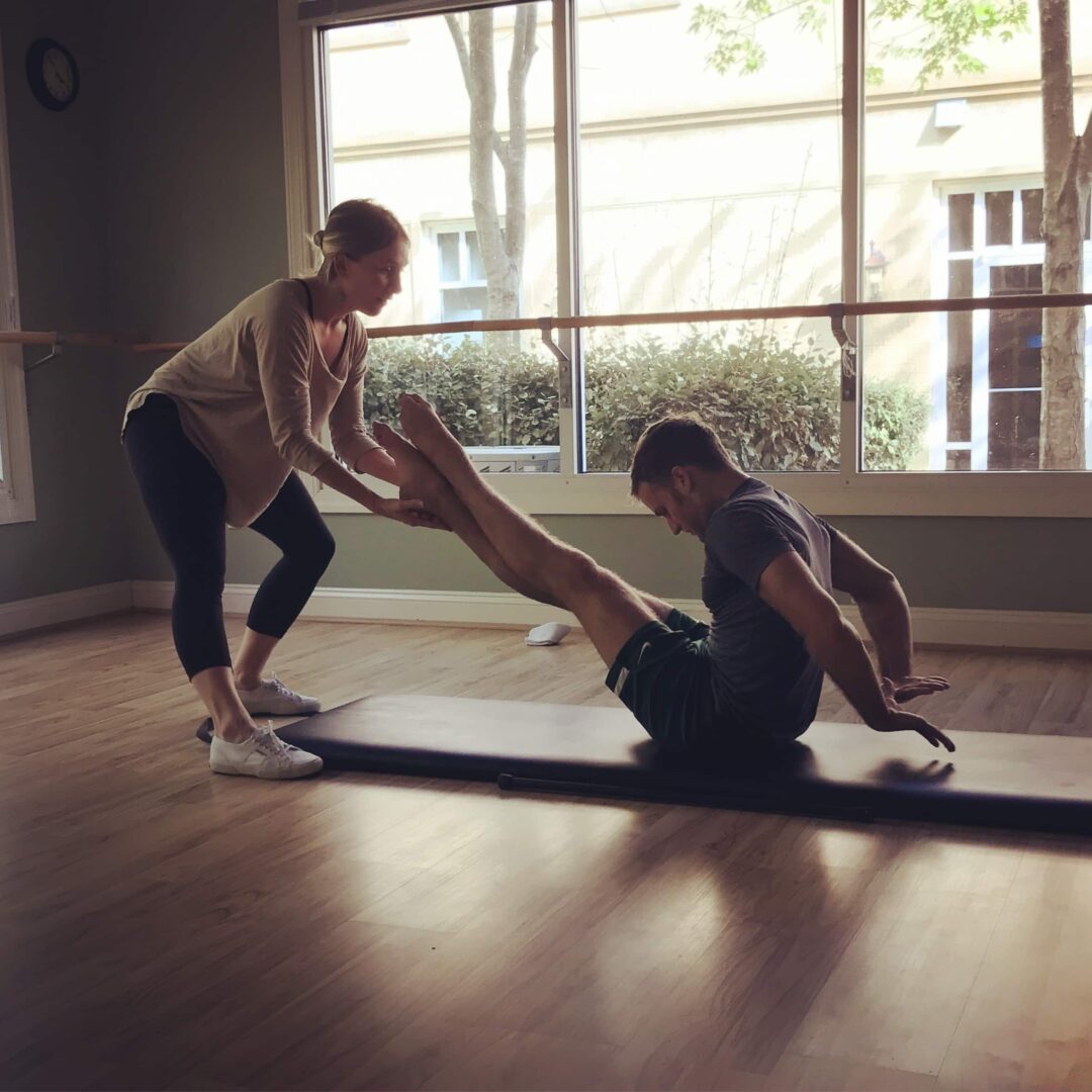 A woman and man are doing yoga on the floor.