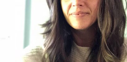 Woman with long hair and bangs smiling.