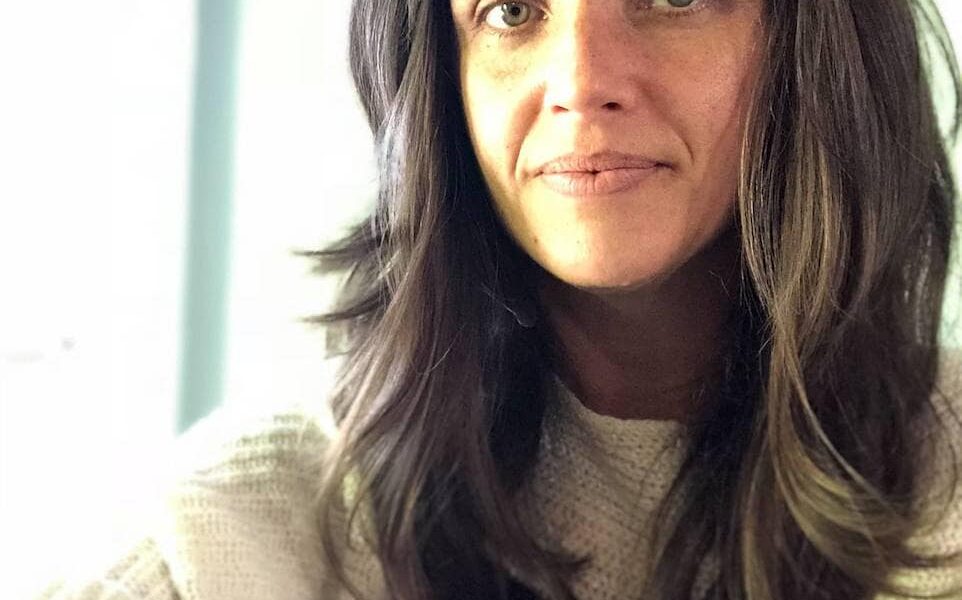 Woman with long hair and bangs smiling.