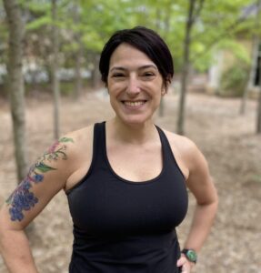 A woman with tattoos standing in the woods.