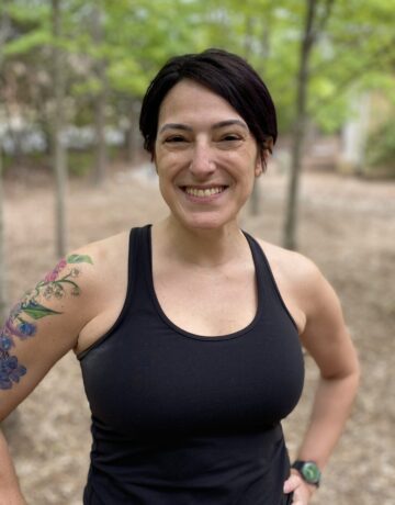 A woman with tattoos standing in the woods.