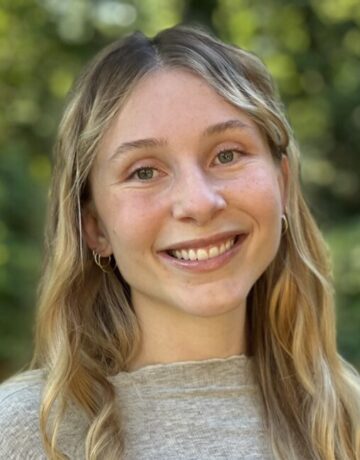 A young woman with long hair smiles for the camera.