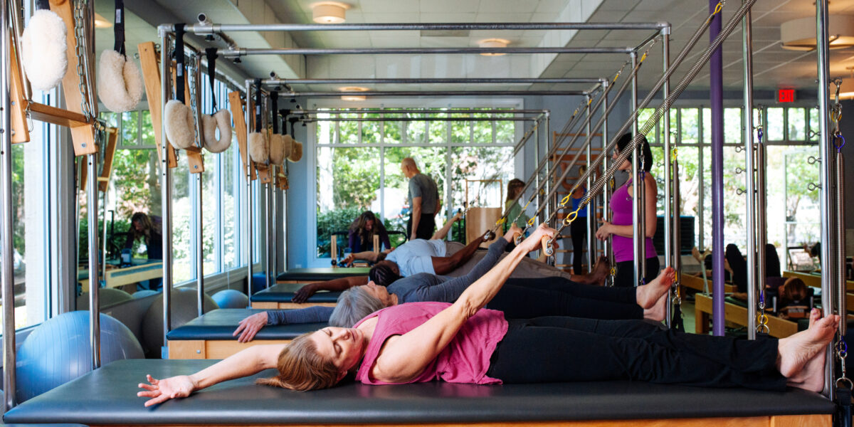 Pilates clients take a side stretch on the Pilates Cadillac