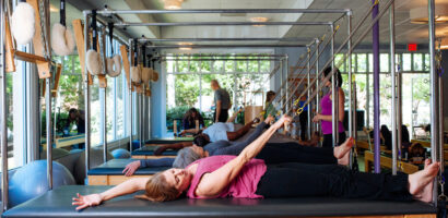 Pilates clients take a side stretch on the Pilates Cadillac
