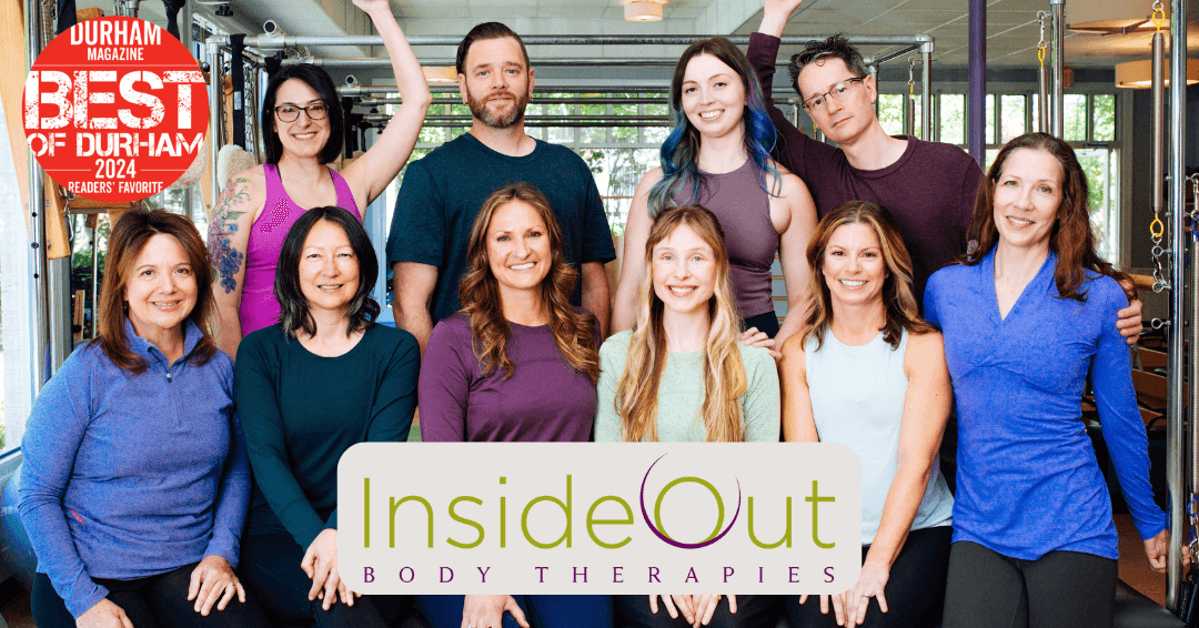 A group photo of the team at InsideOut Body Therapies. Ten people wear shades of purple, blue and green and sit on a Pilates Cadillac, smiling for the camera.