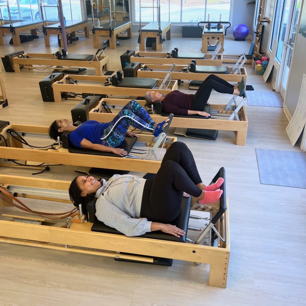 Three Pilates Teacher Trainees work out on the Pilates Reformer Three Pilates Teacher Trainees work out on the Pilates Reformer